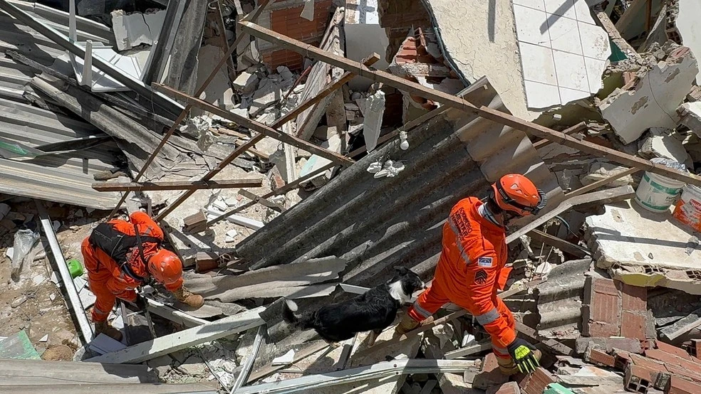 Bombeiros e um cão de busca procuram por cadeirante desaparecida entre os destroços após explosão em Olinda.