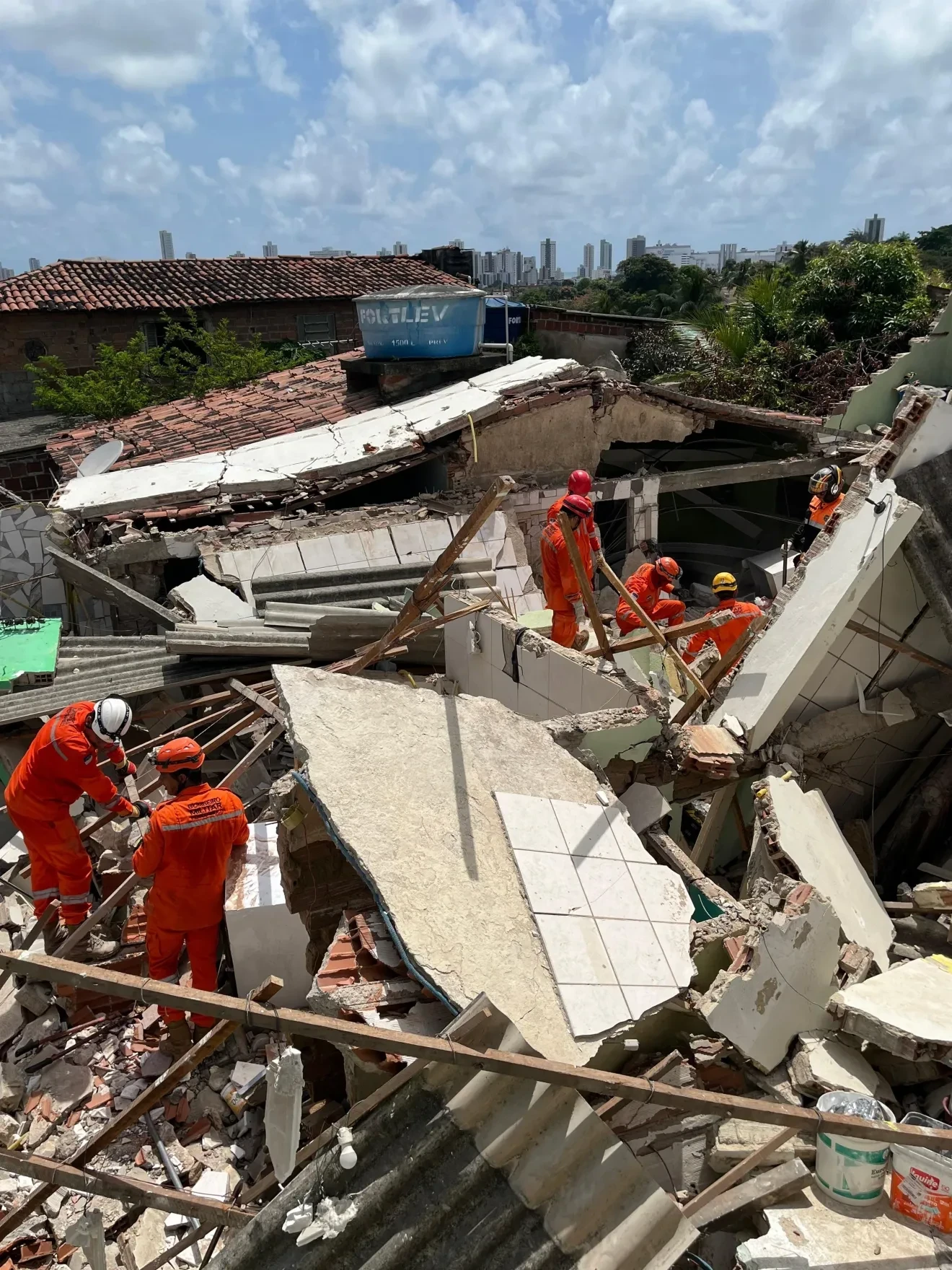 Foi confirmado um falecimento; as equipes continuam as buscas entre os destroços.