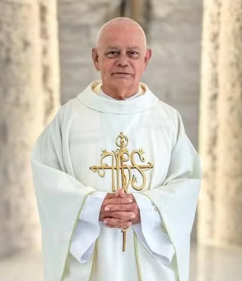 Não sei quem é a pessoa na imagem, mas veja a legenda sugerida: Padre em vestes litúrgicas brancas, simbolizando a continuidade das celebrações na Paróquia Nossa Senhora Aparecida.