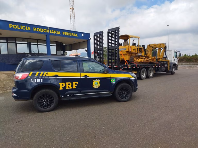 O aviso señalizava que um caminhão carregando um trator em sua carroceria prancha estaria trafegando pela rodovia